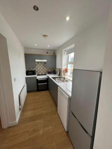 a kitchen with a white refrigerator and a wooden floor at Alpaca farm 3 bed farmhouse THE ALPACA PLACE in Dromara