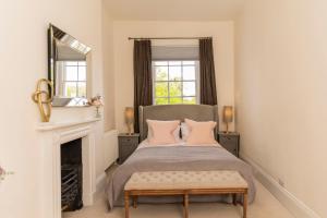 a bedroom with a bed with a fireplace and a mirror at Queens Circus - Montpellier, Central Cheltenham in Cheltenham