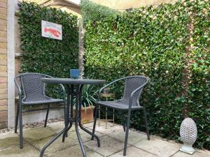 two chairs and a table in front of a hedge at Salt Yard 2 - Stylish Whitstable Cottage - Free Parking - Beach - Harbour in Whitstable