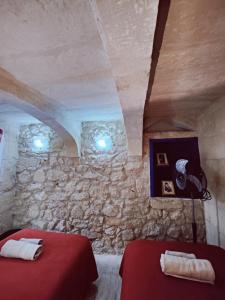 Cette chambre comprend 2 lits et un mur en pierre. dans l'établissement Traditional Maltese Townhouse in Rabat, à Rabat