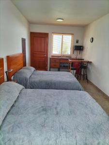 two beds in a room with a desk and a table at KC Hotel & Suites in Comitán