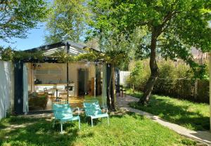a small house with blue chairs in the yard at Le mazet des amants, cabane en bois avec jacuzzi privatif in Avignon