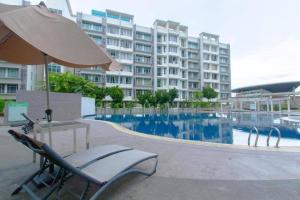 uma cadeira e um guarda-sol junto a uma piscina em Mount austin #Midori Green#Austin Center Quiet Accommodation em Johor Bahru