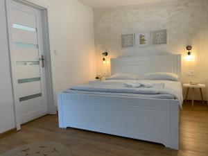 a white bed in a white bedroom with a white bed frame at Apartmány ZELENÝ DOM in Podhájska