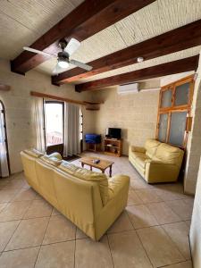 sala de estar con sofás y ventilador de techo. en Nawrat Farmhouse, en Għarb