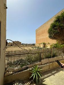 a fence in front of a building with plants at Nawrat Farmhouse in Għarb