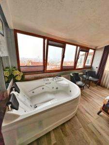 a large white bath tub in a room with windows at Pera Pansiyon in Bursa