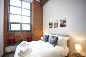 una camera da letto con un letto bianco e un muro di mattoni di The Ruby Suite a Manchester