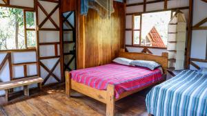 a bedroom with a bed in a room with windows at Casa de Colores in El Zonte