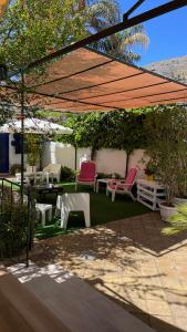 un patio con sillas rosas y mesas bajo un dosel en Alemar Bed & Breakfast, en Mondello