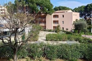 un bâtiment en arrière-plan avec des arbres et des buissons dans l'établissement Magnifique 2 pièces Piscine Parking Plage à pied Tennis, à Vallauris