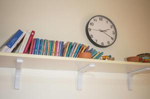 uno scaffale con libri e un orologio a parete di Cifalino - Full Cozy Apartment with Wi-Fi in Catania a Catania Altre 8 foto
