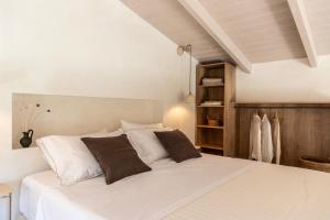 um quarto com uma cama com lençóis brancos e almofadas castanhas em Montesea - Luxury Nature Villas em Vasilikos