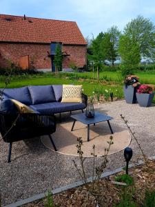 eine blaue Couch und ein Tisch im Hof in der Unterkunft De Weldoeninge in Wingene