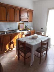 eine Küche mit einem Tisch mit Stühlen und einem Waschbecken in der Unterkunft B&b Su Entu in Muravera