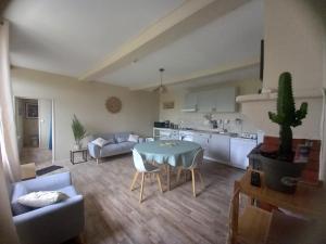 eine Küche und ein Wohnzimmer mit einem Tisch und einem Sofa in der Unterkunft Gîte au centre des plages du débarquement in Isigny-sur-Mer