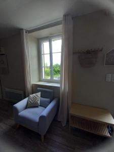 ein Wohnzimmer mit einem blauen Stuhl und einem Fenster in der Unterkunft Gîte au centre des plages du débarquement in Isigny-sur-Mer