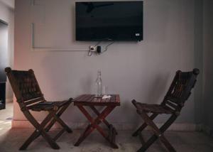 twee stoelen en een tafel met een televisie aan de muur bij Malini Homes Unit - 2 in Guwahati