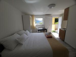a bedroom with a large white bed and a desk at Eden apartment in Kornić