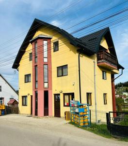 ein großes gelbes Haus mit schwarzem Dach in der Unterkunft Casa Edi in Poiana Negrii