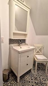 een badkamer met een wastafel, een spiegel en een kruk bij Appartement charmant et spacieux in Auxerre