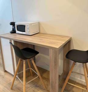 een magnetron bovenop een houten tafel met 2 stoelen bij Duplex 29 tout inclus in Quimper