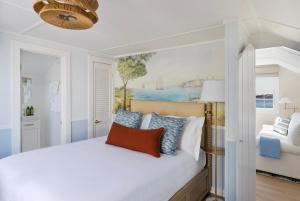 um quarto com uma cama branca e um quadro na parede em The Cottages & Lofts em Nantucket