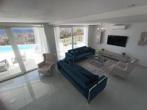 ein Wohnzimmer mit einem Sofa, Stühlen und einem TV in der Unterkunft VILLA NAVIS in Labin