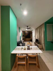 a living room with a green wall and a table and chairs at FJ Haven in Penampang