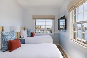 two beds in a room with two windows at The Cottages & Lofts in Nantucket
