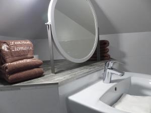 een badkamer met een wastafel en een spiegel op een aanrecht bij Pension Ziemann in Nartum