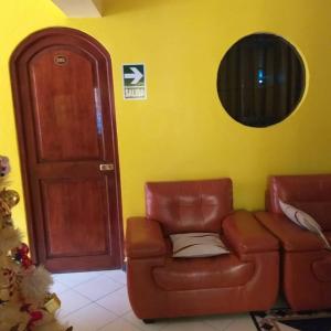 una sala de estar con una silla de cuero marrón y una puerta en HOSPEDAJE KAROL, en Ayacucho
