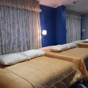 2 camas en una habitación con paredes y cortinas azules en HOSPEDAJE KAROL en Ayacucho