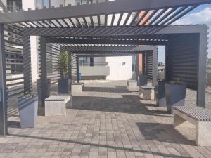 a pergola with benches and plants on a patio at City Junction Windhoek in Windhoek
