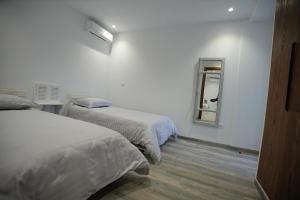 a white room with two beds and a mirror at Le gris Perle in Sfax