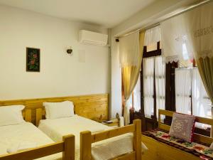 a bedroom with two beds and a window at Medieval Rooms in Gjirokastër