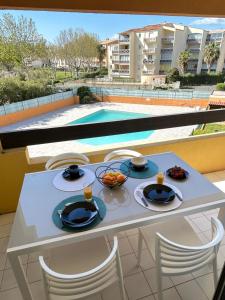 CAP AU CAP - T3 avec Clim WIFI Vue piscine proximité plage Richelieu في كاب داغد: طاولة مع أطباق من الطعام على شرفة مع مسبح