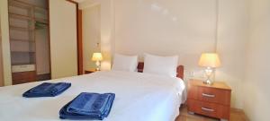 una camera da letto con un letto bianco con due asciugamani blu di Golden Delight Central Apartment a Skopje Altre 62 foto