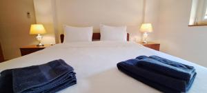 1 dormitorio con 1 cama blanca y 2 toallas azules en Golden Delight Central Apartment, en Skopje