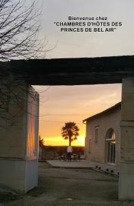 a sunset behind a building with a tree and a bench at Chambres d'hôtes des Princes de Bel Air in Loudun