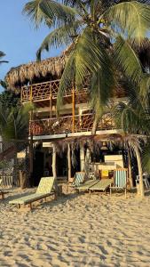 een gebouw op het strand met stoelen en palmbomen bij Cabaña Punta Coral in Rincón