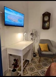 Cette chambre comprend un bureau blanc, un réveil et une chaise. dans l'établissement Room in Ain Karem - A Maltese Traditional Townhouse, à Mosta