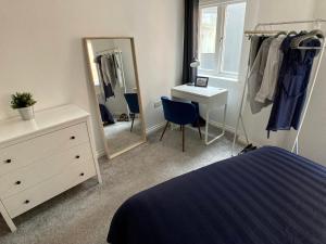a bedroom with a bed and a dresser and a mirror at Emily Lane Apartments in Belfast