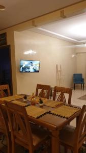 uma mesa de jantar e cadeiras com uma televisão na parede em Appartement Mohammed V Airport Top em Deroua