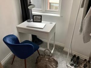 una scrivania bianca con computer portatile e sedia blu di Emily Lane Apartments a Belfast