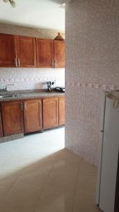eine Küche mit Holzschränken und einem weißen Kühlschrank in der Unterkunft Appartement Mohammed V Airport Top in Deroua
