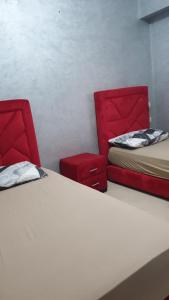 een kamer met 2 bedden en 2 rode stoelen bij Appartement Mohammed V Airport Top in Deroua