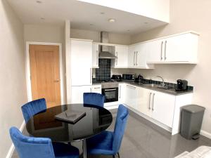 a kitchen with a glass table and blue chairs at Cathedral Quarter Apartments in Belfast