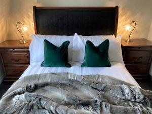 a bed with two green pillows and a blanket at Cathedral Quarter Apartments in Belfast
