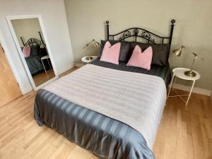 um quarto com uma cama grande e 2 almofadas cor-de-rosa em Little Victoria Apartments em Belfast